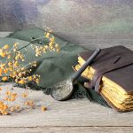 La cuillère BINTOU en céramique artisanale posée sur une table à côté d'un livre.