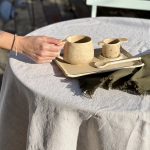 Le set à thé RIKU est posé sur une table dans le jardin et je prends le mug en céramique artisanale.