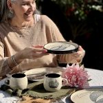 Assiette LE PINGOUIN en céramique artisanale tenue à la main sur une table dressée