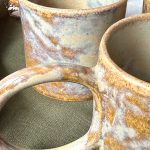 Deux mugs GARANCE en céramique artisanale en gros plan, montrant l'anse et le détail de l'émail du deuxième mug.