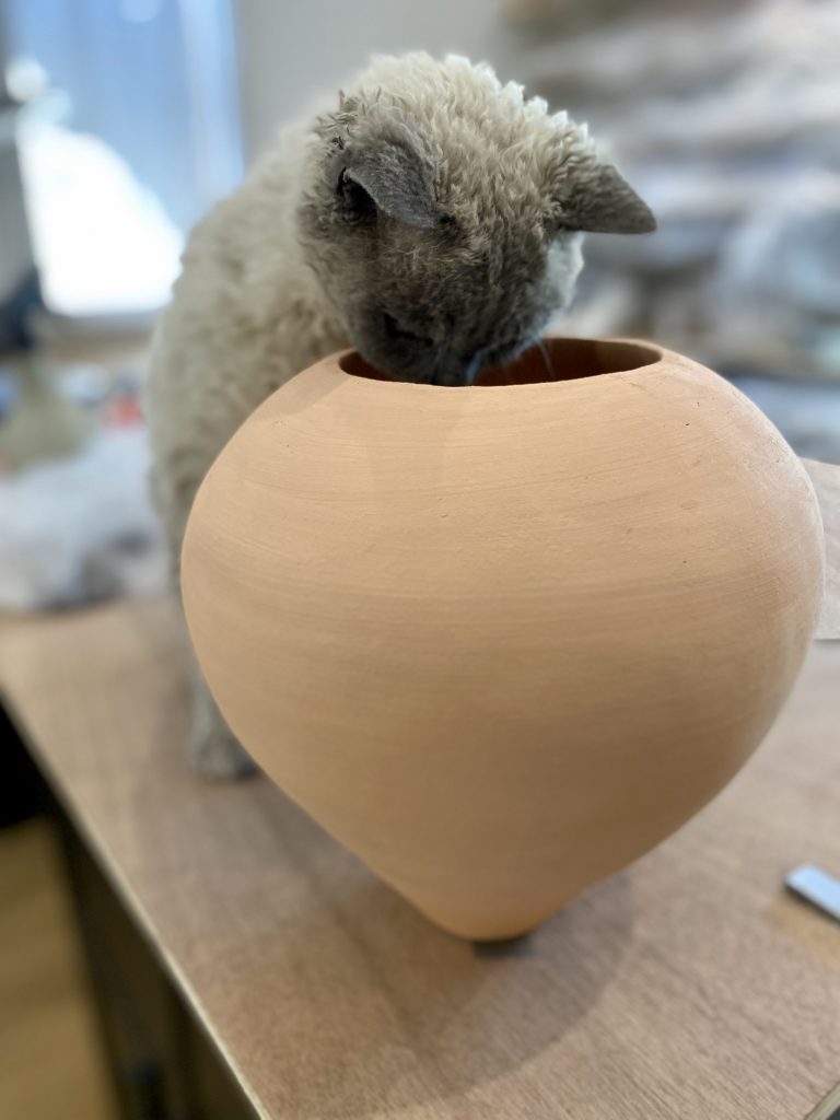 Tao qui regarde l'intérieur du vase en grès dans mon atelier de céramique artisanale.