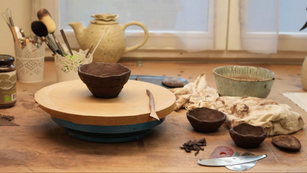Plan de travail dans mon atelier avec une pièce en grès noire sur la tournette et mes outils de modelage.