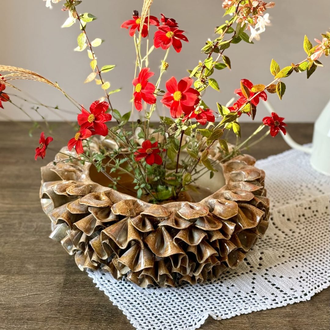 Vase ÉMILE en céramique artisanale posé sur une table avec un napperon, vu de profil, avec les fleurs bien visibles dans le dôme.