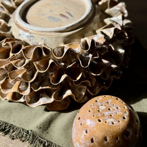 Vue rapprochée du vase ÉMILE en céramique artisanale retourné, montrant son pied et le dessous émaillé, avec le dôme posé à côté.