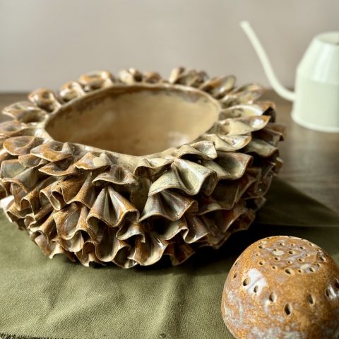 Vase ÉMILE en céramique artisanale avec son dôme perforé posé à côté, présenté sur une table.