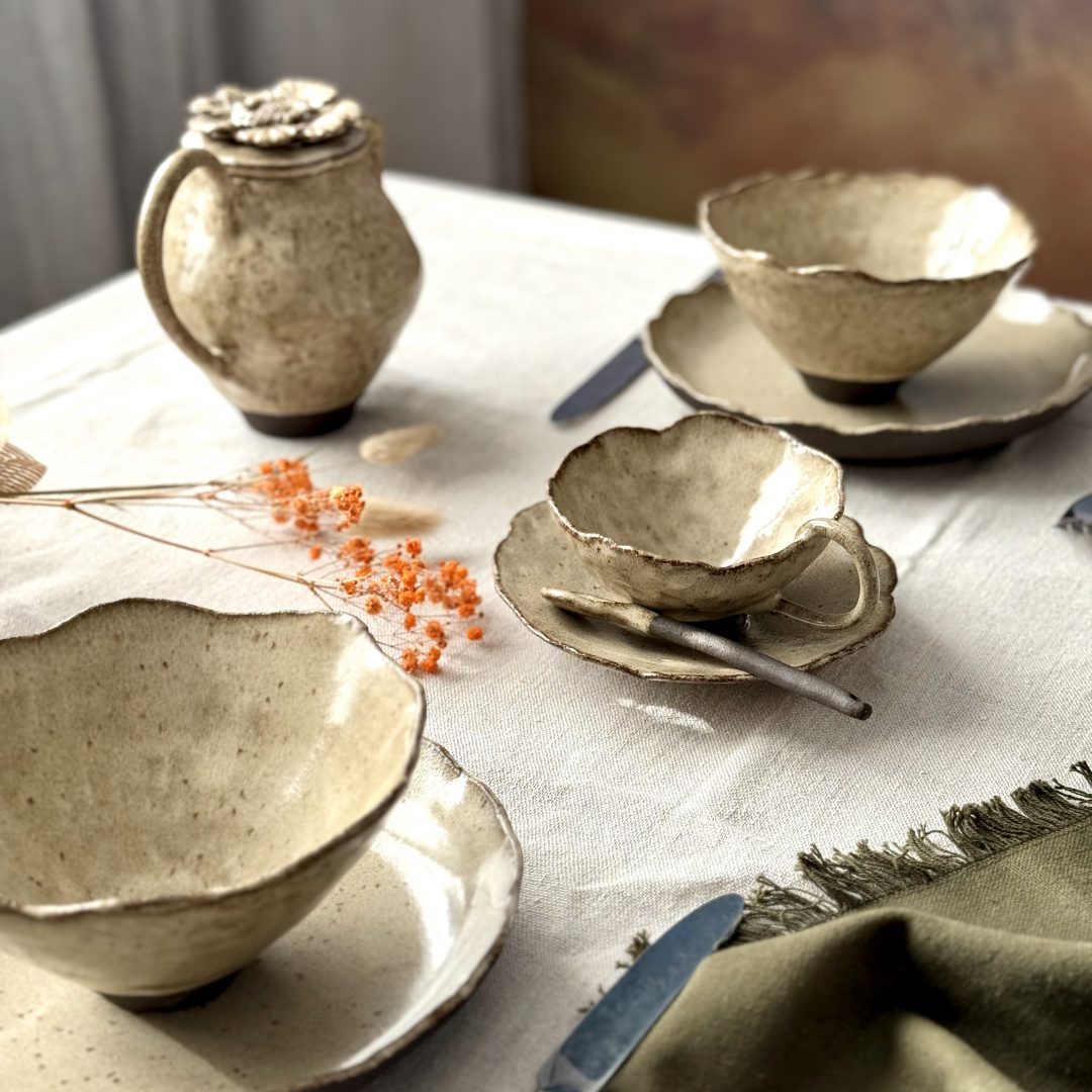Table dressée avec les pièces de la collection FLOR en céramique artisanale, dont la tasse Lilium, la sous-tasse Dahlia et la cuillère Rosa, présentées en situation.
