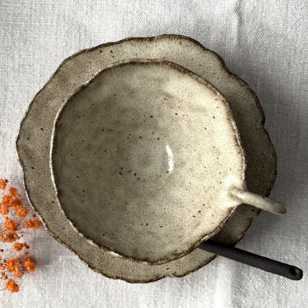 Vue rapprochée de la tasse Lilium posée sur la sous-tasse Dahlia, avec la cuillère Rosa placée dessus, photographiée depuis le dessus.