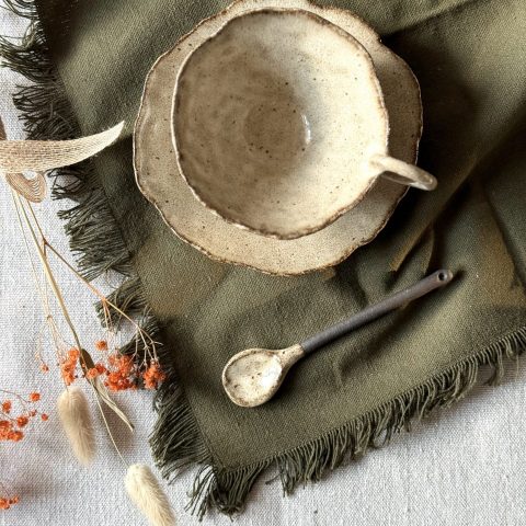 La tasse lilium, la sous-tasse dahlia et la cuillère rosa vue du dessus sur une table.