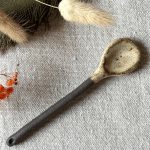 La cuillère Rosa en grès noir posée sur une table.