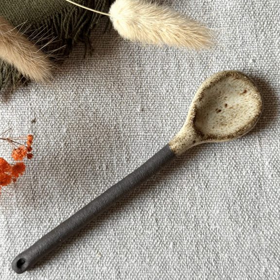 La cuillère Rosa en grès noir posée sur une table.