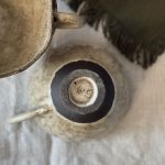 Tasse Aster retournée vue du dessus, montrant le dessous de la pièce en grès noir et la signature artisanale.