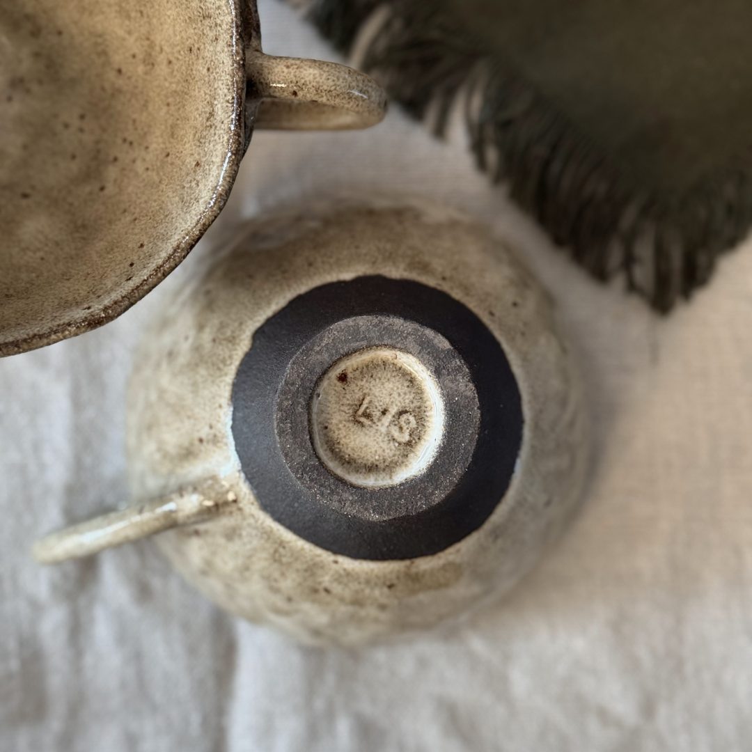 Tasse Lilium retournée vue du dessus, montrant le dessous de la pièce en grès noir et la signature artisanale.