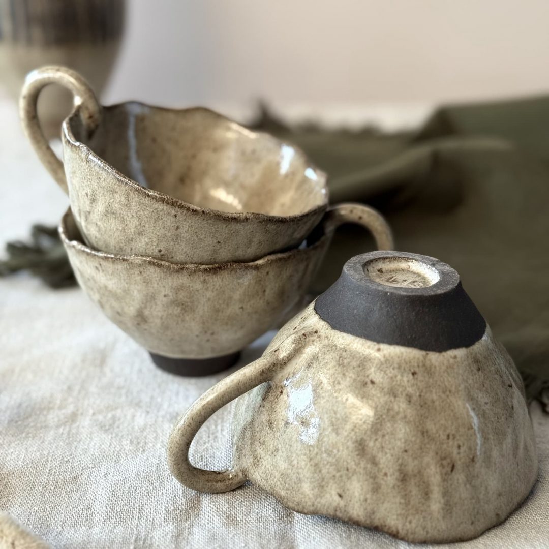 Dessous de la tasse Aster retournée avec la signature de Lis Céramique, posée sur une table, avec d’autres tasses Aster.