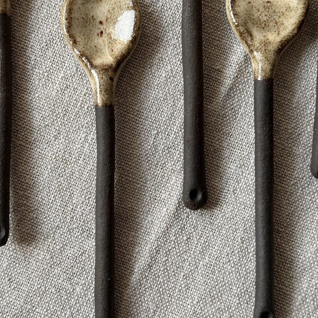 Plusieurs cuillères Rosa en grès noir posées sur une table.