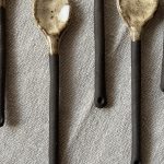 Plusieurs cuillères Rosa en grès noir posées sur une table.