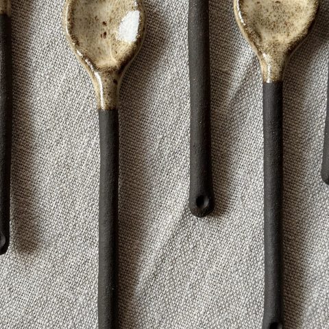 Plusieurs cuillères Rosa en grès noir posées sur une table.