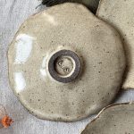 Sous-tasse Dahlia en grès noir retournée montrant le dessous signé.