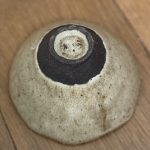 Bol camellia retournée vue du dessus, montrant le dessous de la pièce en grès noir et la signature