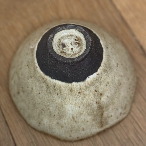 Bol camellia retournée vue du dessus, montrant le dessous de la pièce en grès noir et la signature