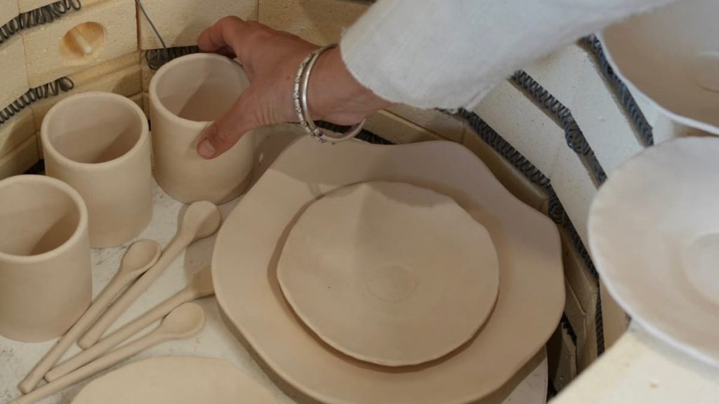 Je sors une tasse biscuitée de mon four juste après la première cuisson.