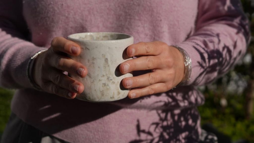 Je tiens la tasse ASTRAL en céramique artisanale entre mes mains pour montrer les détails de l'émail.