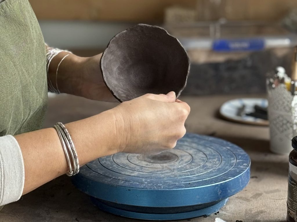Façonner une tasse en grès noir au pincé.