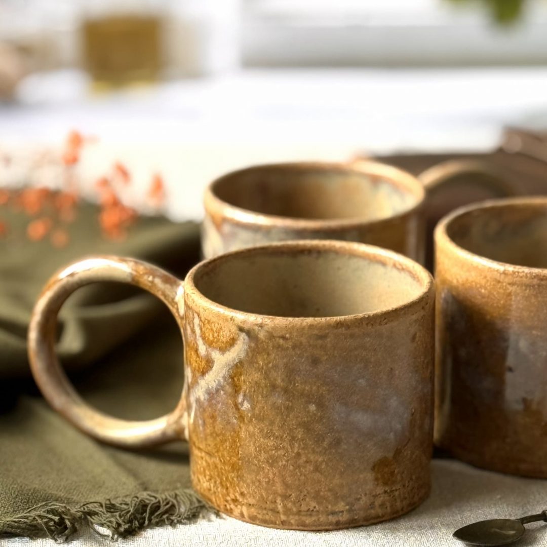 Plusieurs mugs Garance en grès artisanal posés sur une table.