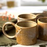 Plusieurs mugs Garance en grès artisanal posés sur une table.