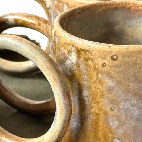 Gros plan sur trois mugs GARANCE en grès artisanal, montrant l'anse ronde et le détail de l'émail.