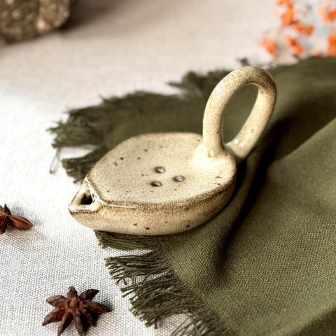 Lampe à huile Stella fait main en grès noir posée sur une table.