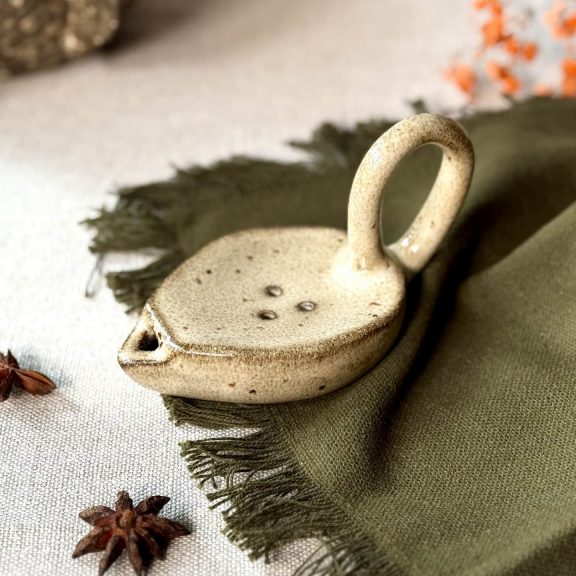 Lampe à huile Stella fait main en grès noir posée sur une table.