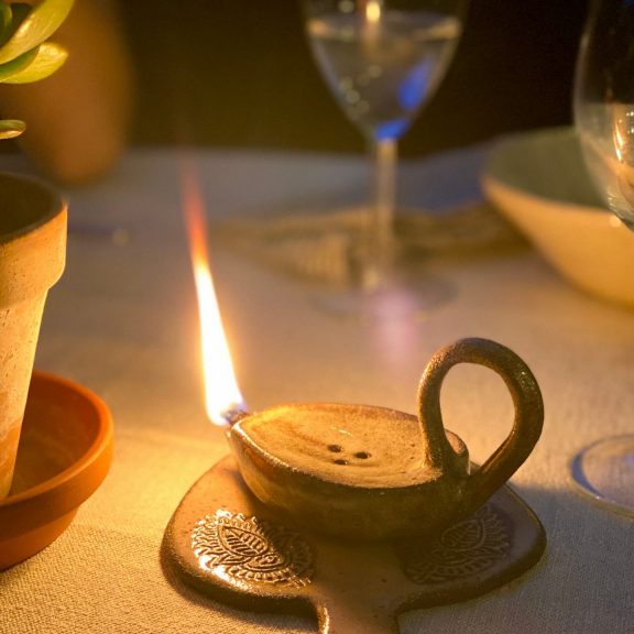 Lampe à huile Stella en grès noir allumée posée sur une table dressée.