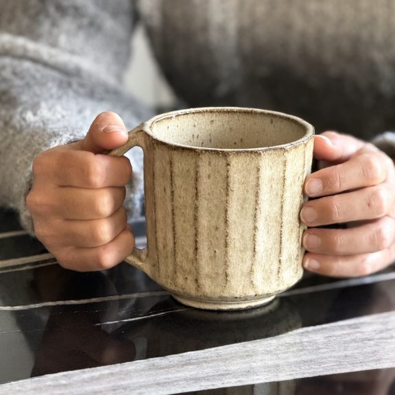 Mug artisanal en grès utilisé pour boisson chaude.