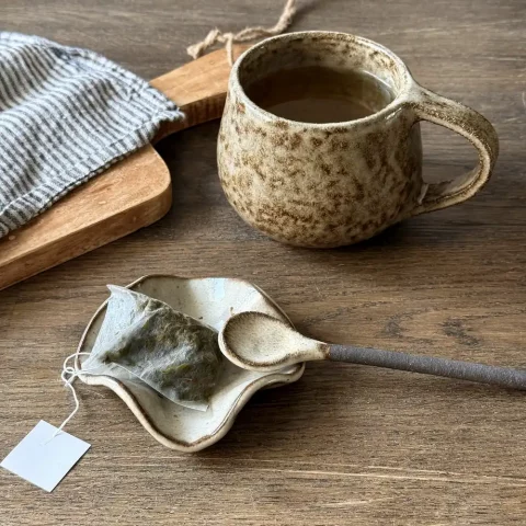 Coupelle léa en céramique artisanale avec un sachet de thé et la cuillère rosa et le mug coumba avec un thé