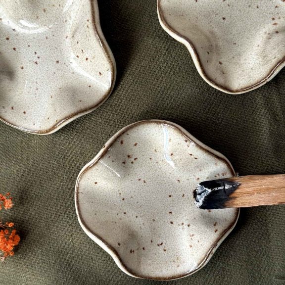 Plusieurs coupelles Léa en grès noir posées sur une table avec un palo santo sur l'une d'entre elle.