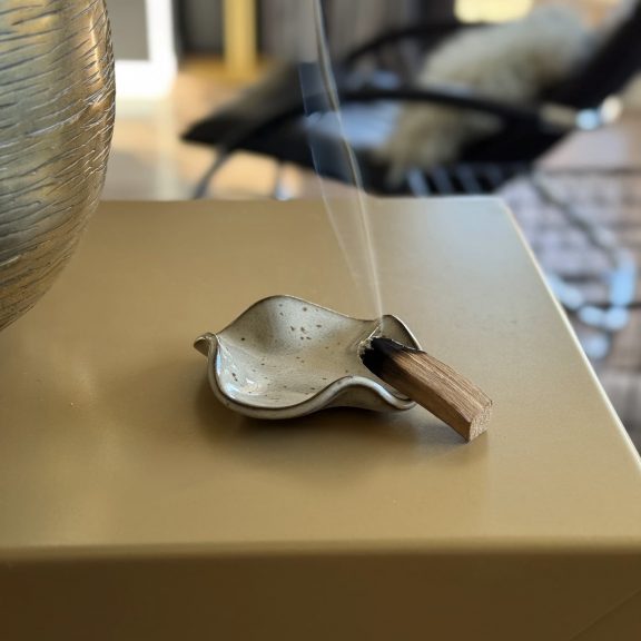 Coupelle Léa en céramique artisanale posée sur une console dans le salon avec un palo santo qui brûle sur la coupelle.