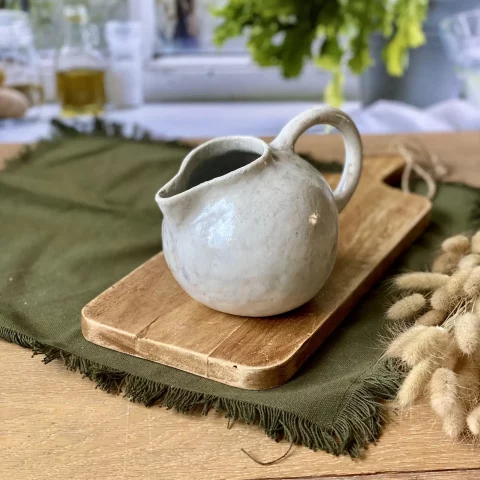 Saucière Cosmos en céramique artisanale blanche sur planche en bois, vu de profil.