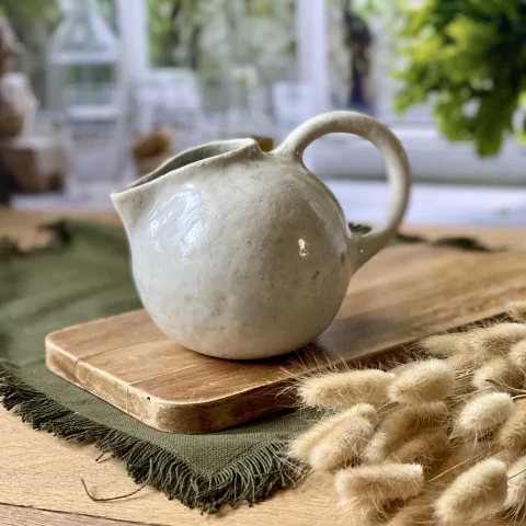 Saucière Cosmos en grès artisanal blanc posée sur une planche en bois, ambiance naturelle.
