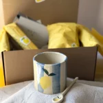 Coffret citron en céramique artisanale avec tasse et cuillère sur une table.