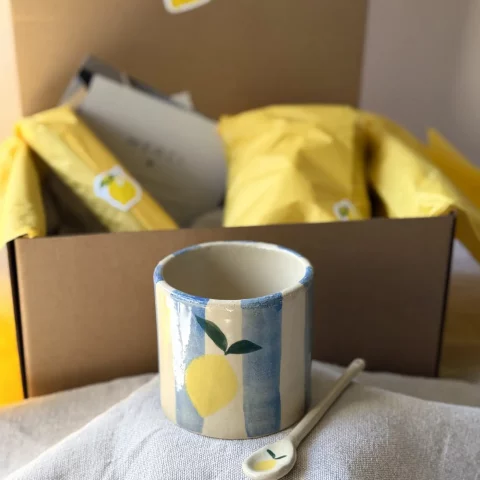 Coffret citron en céramique artisanale avec tasse et cuillère sur une table.