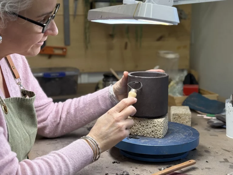 céramiste qui façonne une tasse en grès noir dans son atelier