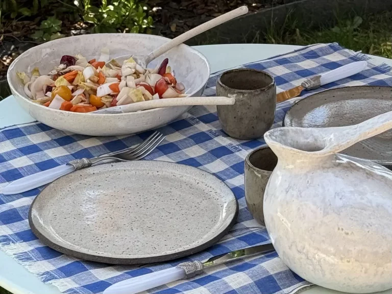 Vaisselle artisanale en grès sur une table à l'extérieur.