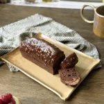 Plat nora en céramique artisanale avec un cake et le mug Garance sur une table.