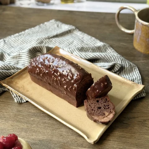 Plat nora en céramique artisanale avec un cake et le mug Garance sur une table.