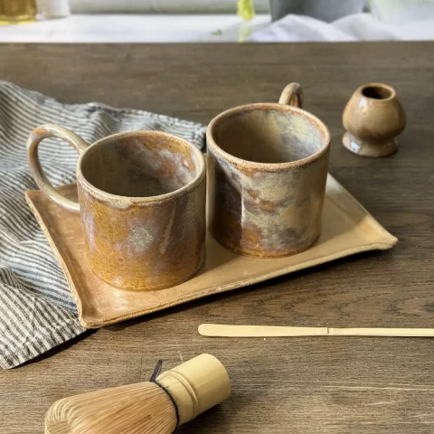 Plat nora en grès artisanal avec deux mug garance et le support à matcha nori posés sur une table