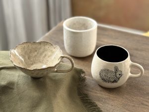 Plusieurs tasses et mugs en céramque artisanale sur une table.